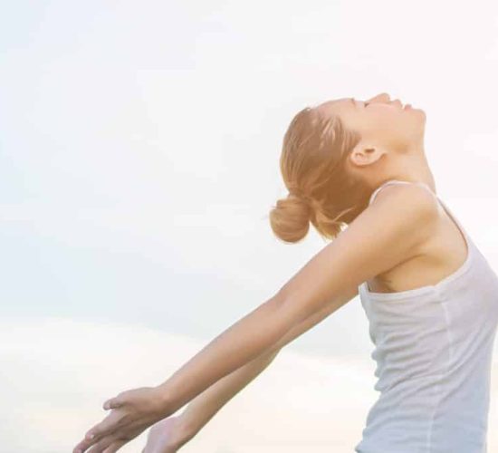 Young beautiful woman raising hands with beautiful view at meadow enjoy fresh air.