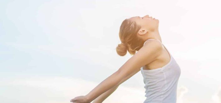 Young beautiful woman raising hands with beautiful view at meadow enjoy fresh air.